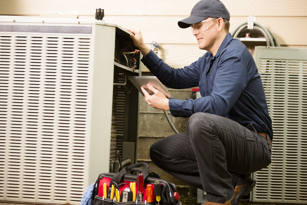 Air conditioner repairman works on home unit. Blue collar worker.