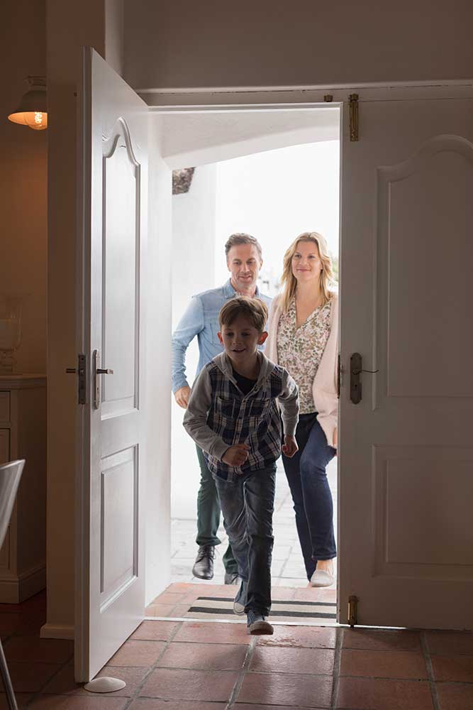 a family walking through the front door of home